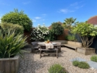 South-facing garden at The Rock in summer with wooden deck, picnic table, and lush green planting