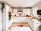 White fitted kitchen at The Rock with wooden worktops, extractor hood, built-in oven, and octopus wall art