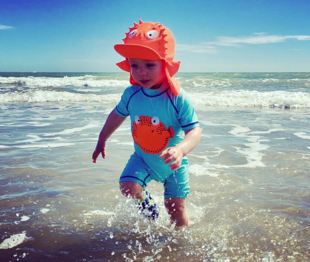 Toddler enjoying a paddle in the sea at Camber Sands on a sunny day